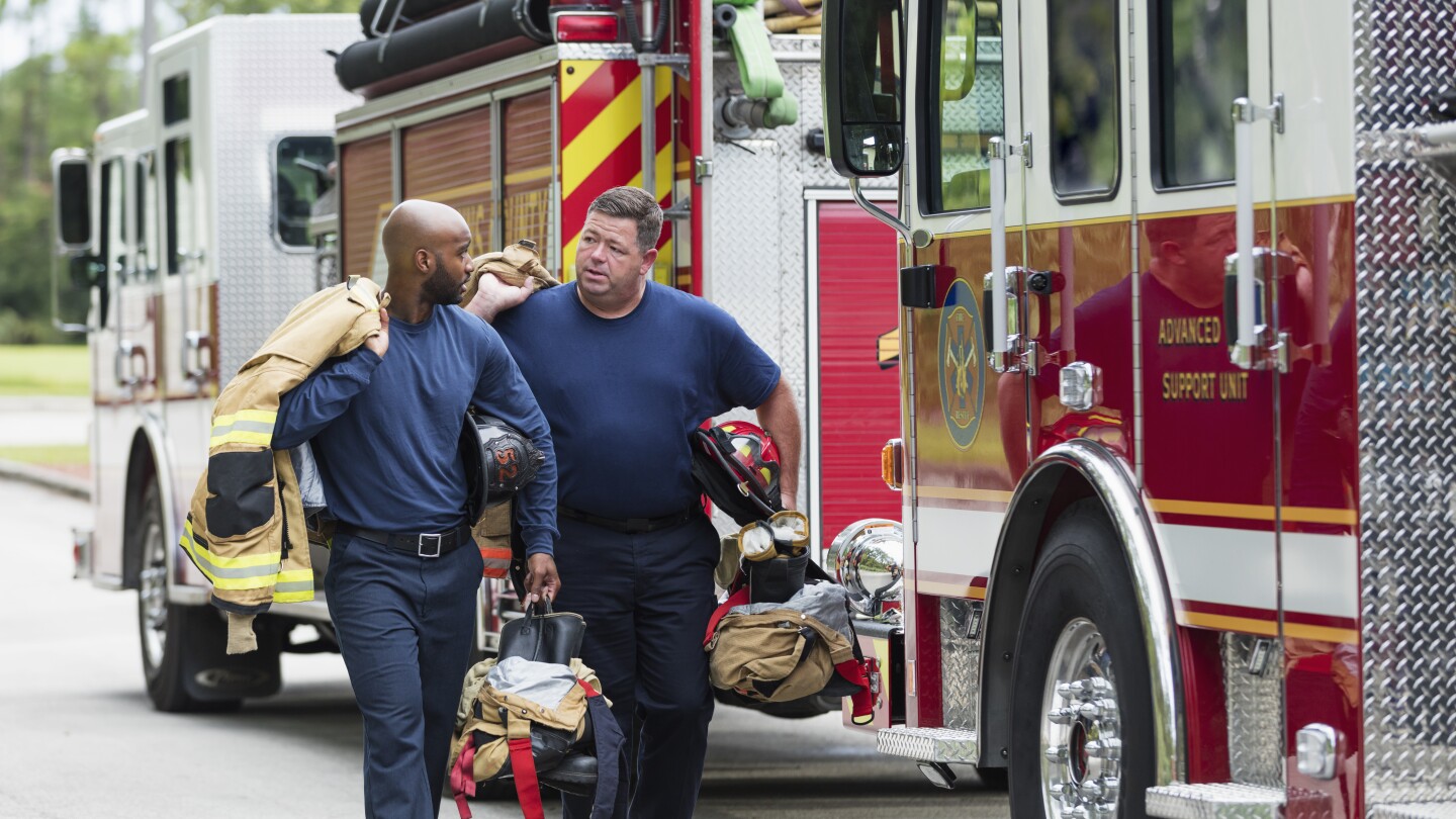 Two firefighters walking, talking by fire engines