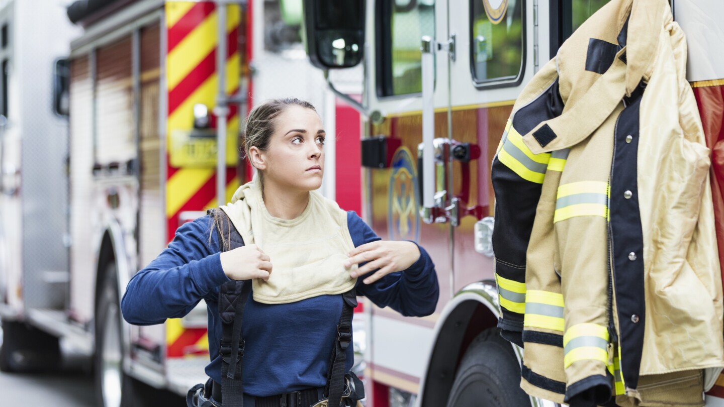 Female firefighter putting on protective suit