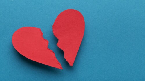 Broken paper heart on blue background, top view