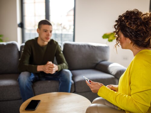 Caring female therapist talking with insecure teenage boy