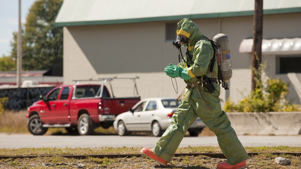 HazMat firefighter walking in a field with a camera