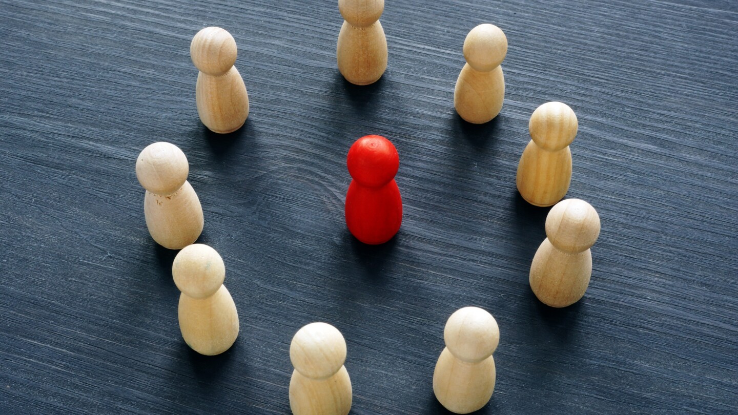 Circle from wooden figures and red figure. Discrimination or harassment concept.